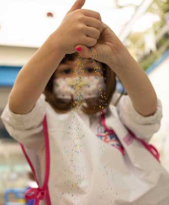 Criança explorando flocos coloridos - Ensino Fundamental Uniepre